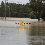 A flooded road in Australia, with a yellow sign saying water over road