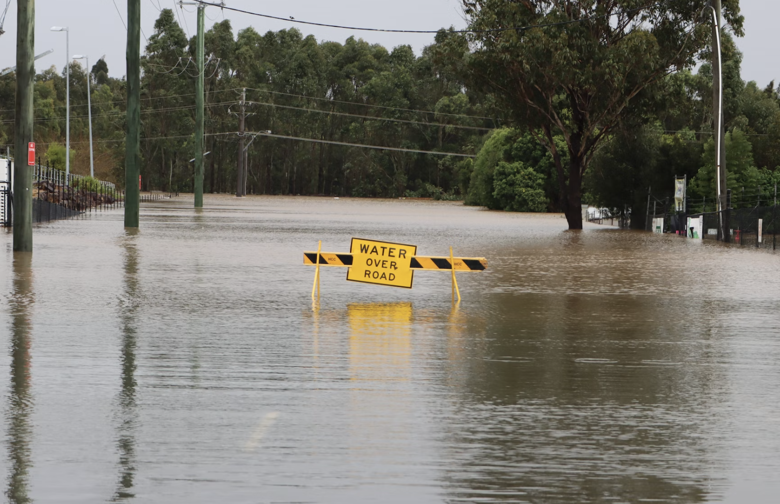 A flooded road in Australia, with a yellow sign saying water over road