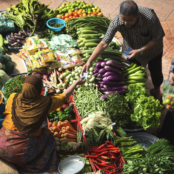 a woman and man exchanging money at a food market stand