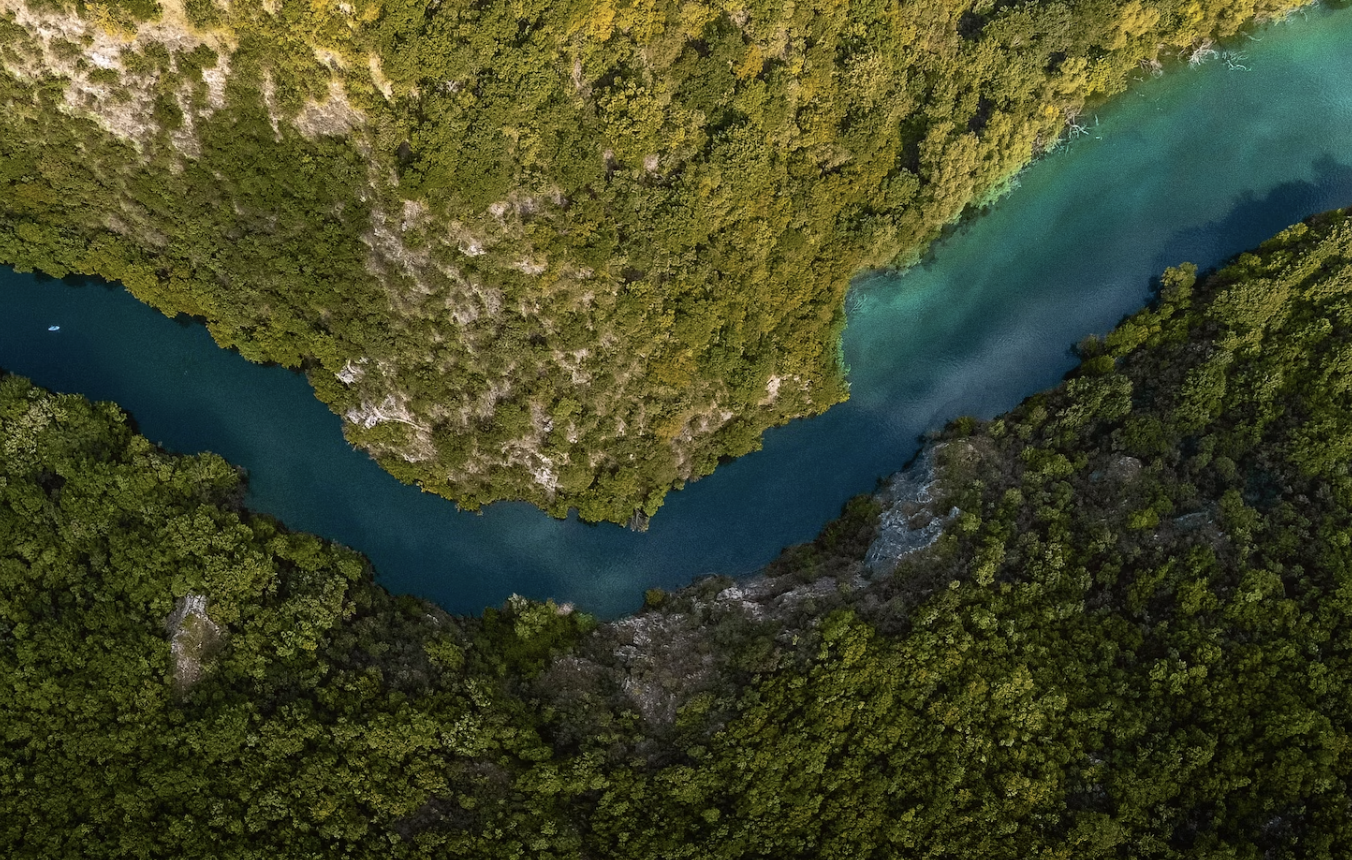 An aerial view of a blue river meandering through green vegetation